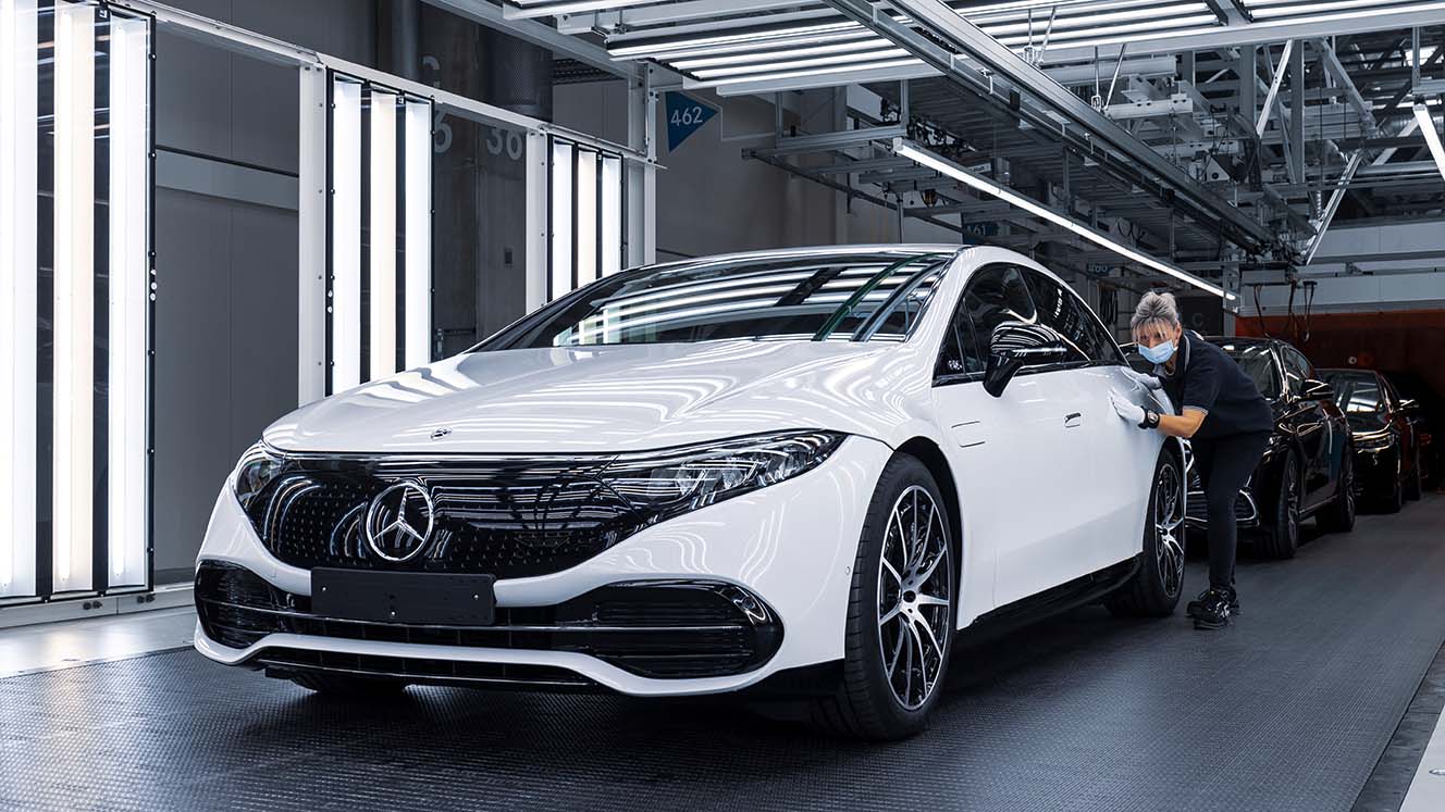 Eine Mitarbeiterin prüft den Lack eines fabrikneuen Mercedes